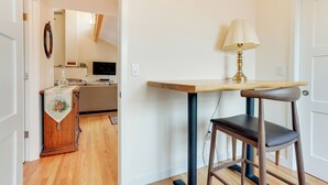 A small, well-lit room with a wooden table and a single chair. A lamp is on the table, and a decorative item hangs on the wall. - Beautiful Seattle Home w/ Patio ~ 9 Mi to Downtown (Seattle)
