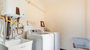 A laundry room with a washing machine, dryer, and a sink with hoses. - Beautiful Seattle Home w/ Patio ~ 9 Mi to Downtown (Seattle)