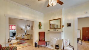 Amplia sala de estar con chimenea, un candelabro y un espejo grande. Hay varias sillas y un sofá.