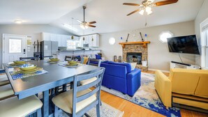 A modern kitchen with white cabinets, a dining table with blue placemats, and a blue sofa in the living area. - Lakefront Eatonton Getaway w/ Dock & Grill! (Eatonton)