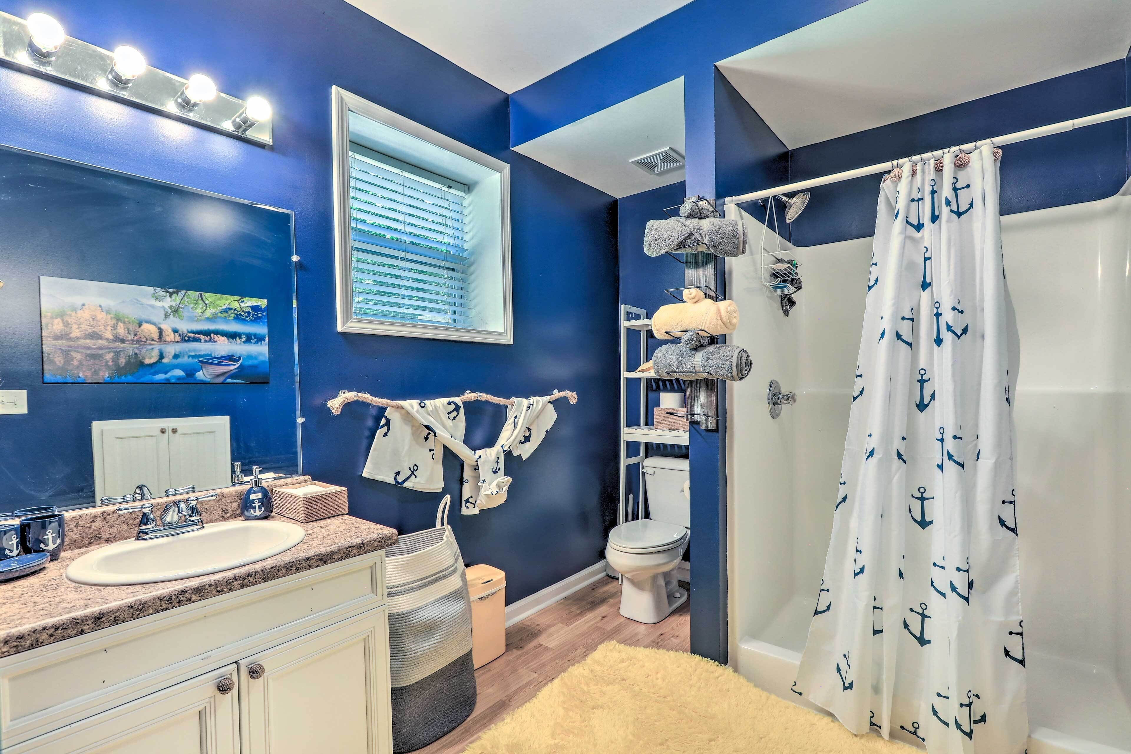 Une salle de bain équipée d’un lavabo, de toilettes et d’un rideau de douche orné de motifs d’ancres.