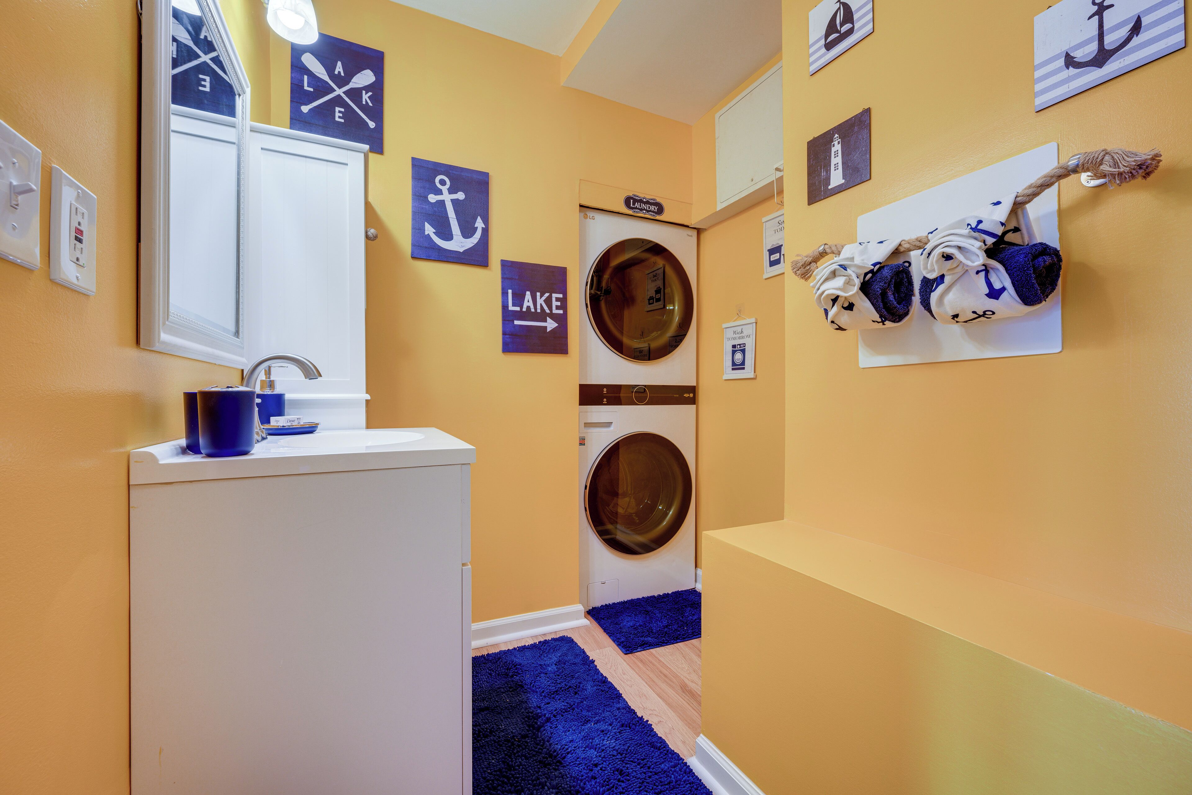 A laundry area with a washing machine, a sink, and a mirror.