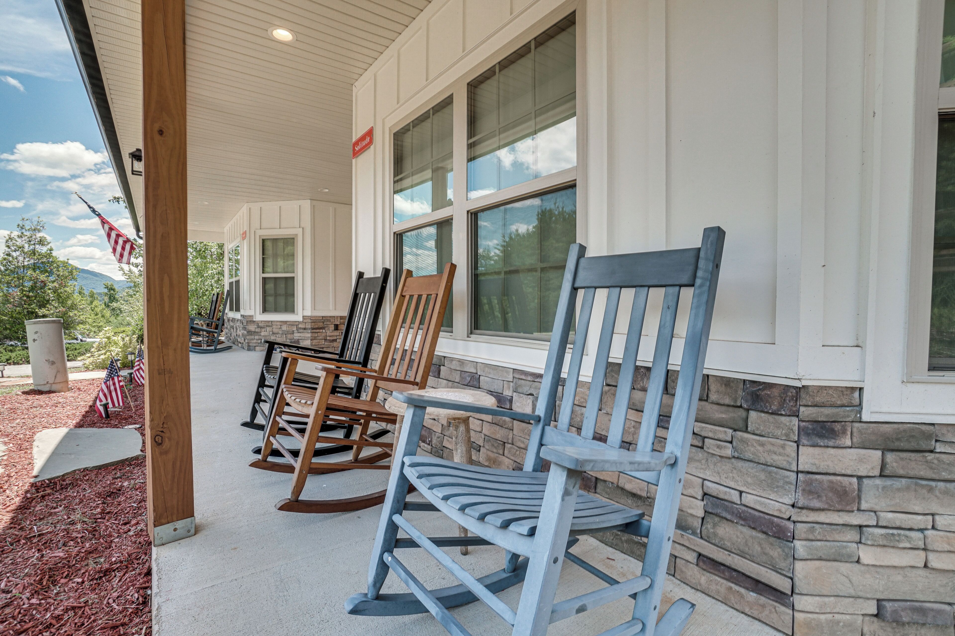 A porch with rocking chairs and a stone wall.