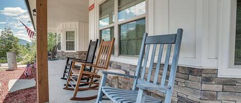 A porch with rocking chairs and a stone wall.