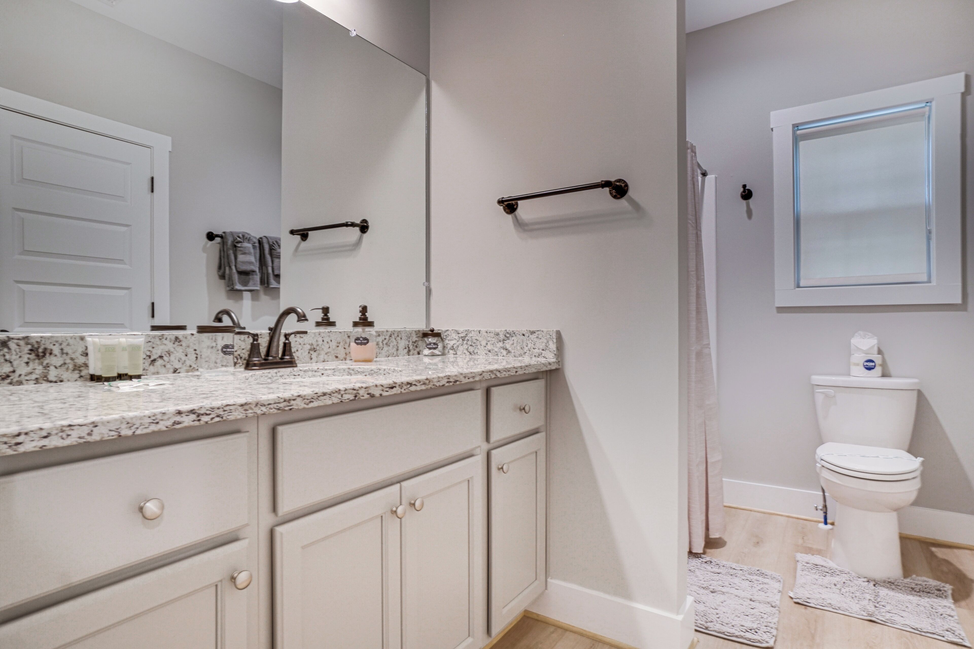 A bathroom with a white sink, mirror, and toilet. There are towels on the towel rack and a shower curtain.