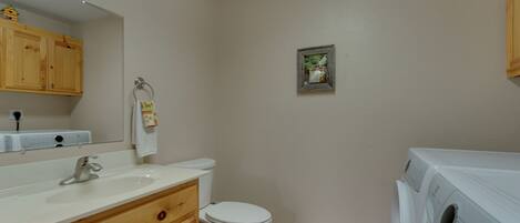 A bathroom with a sink, toilet, and a washing machine.