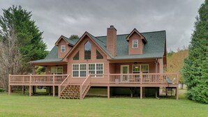 A large, two-story log cabin with a wrap-around porch and a chimney.