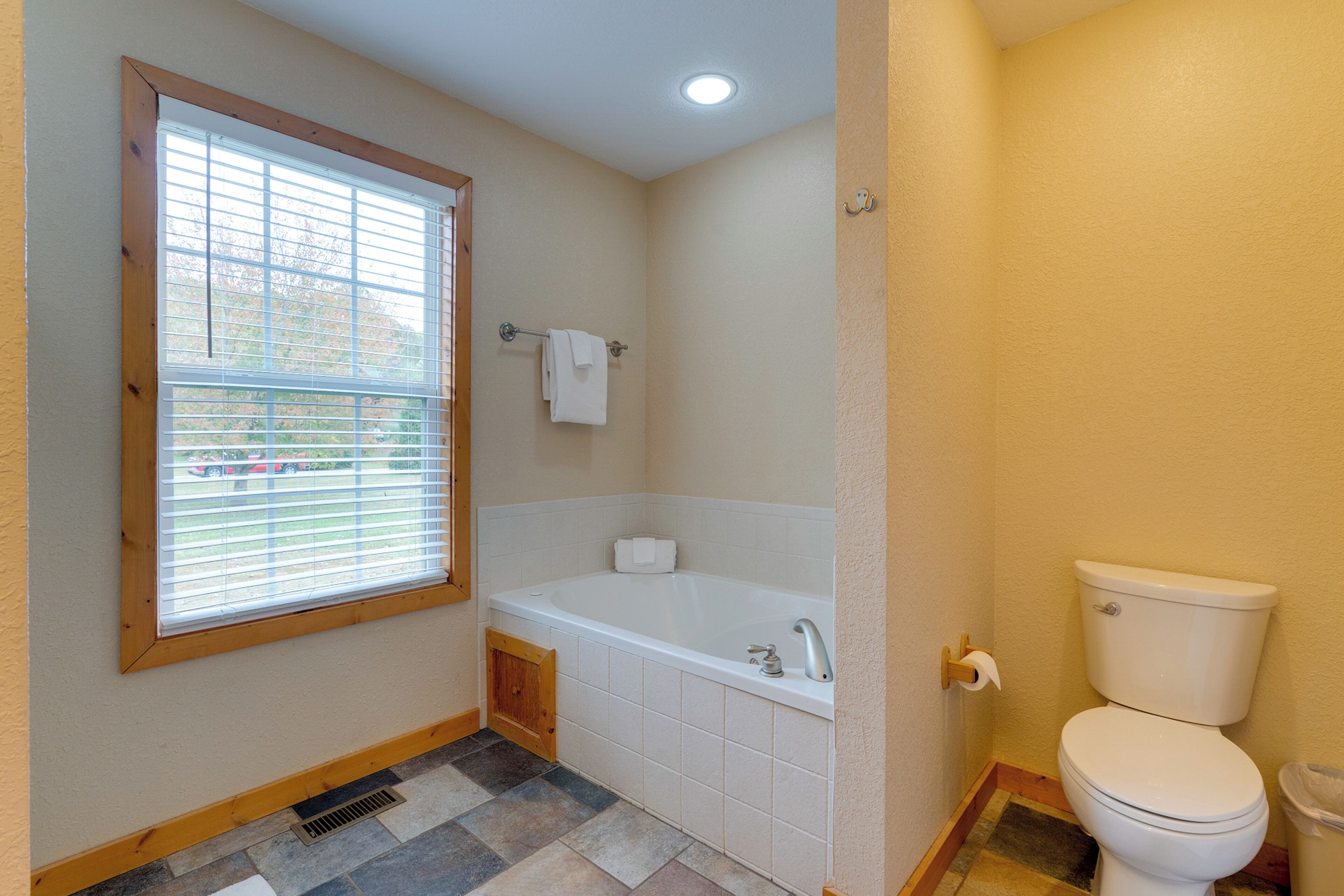 A bathroom with a bathtub, toilet, and window.
