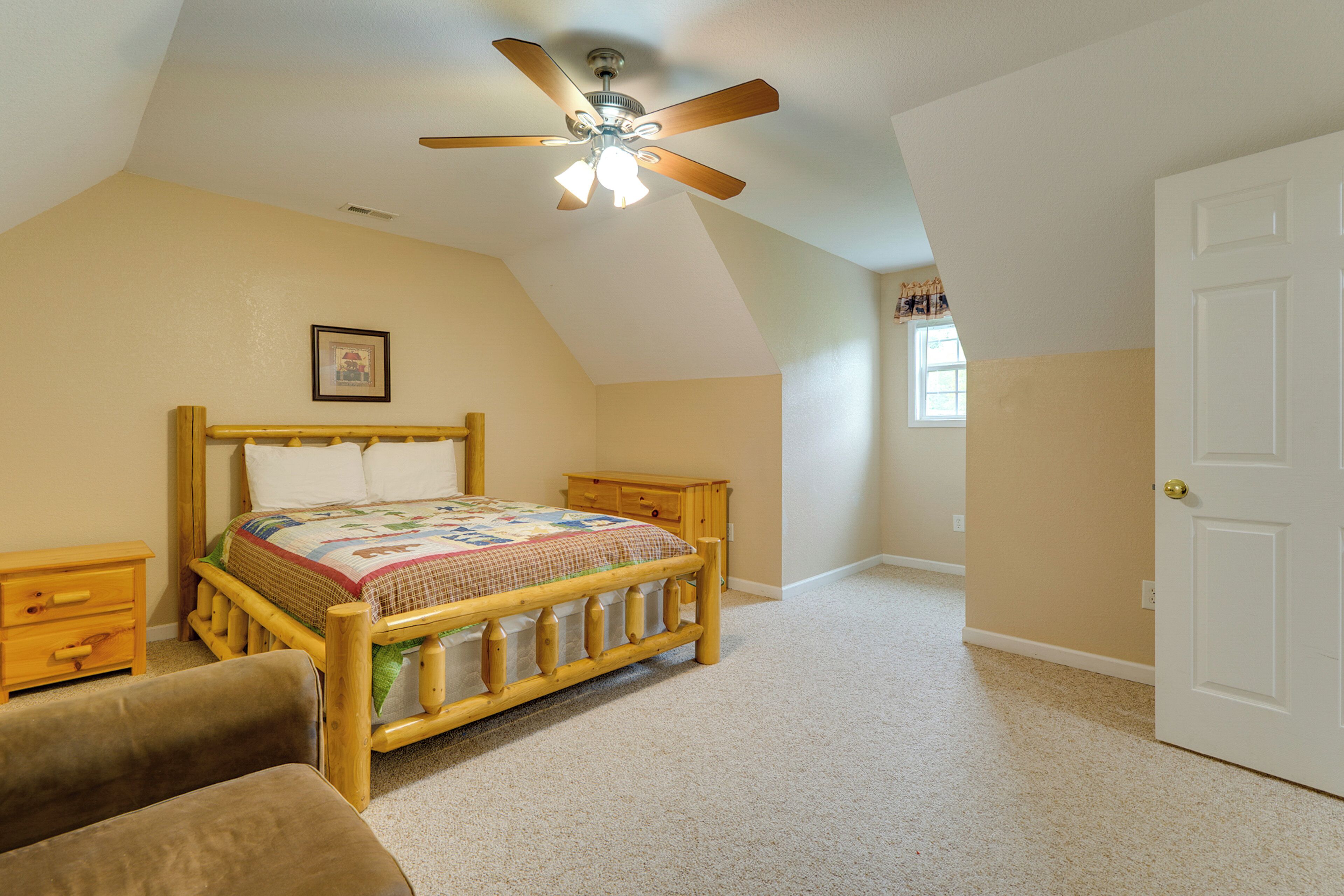 A bedroom with a wooden bed, a ceiling fan, a window, and a door.
