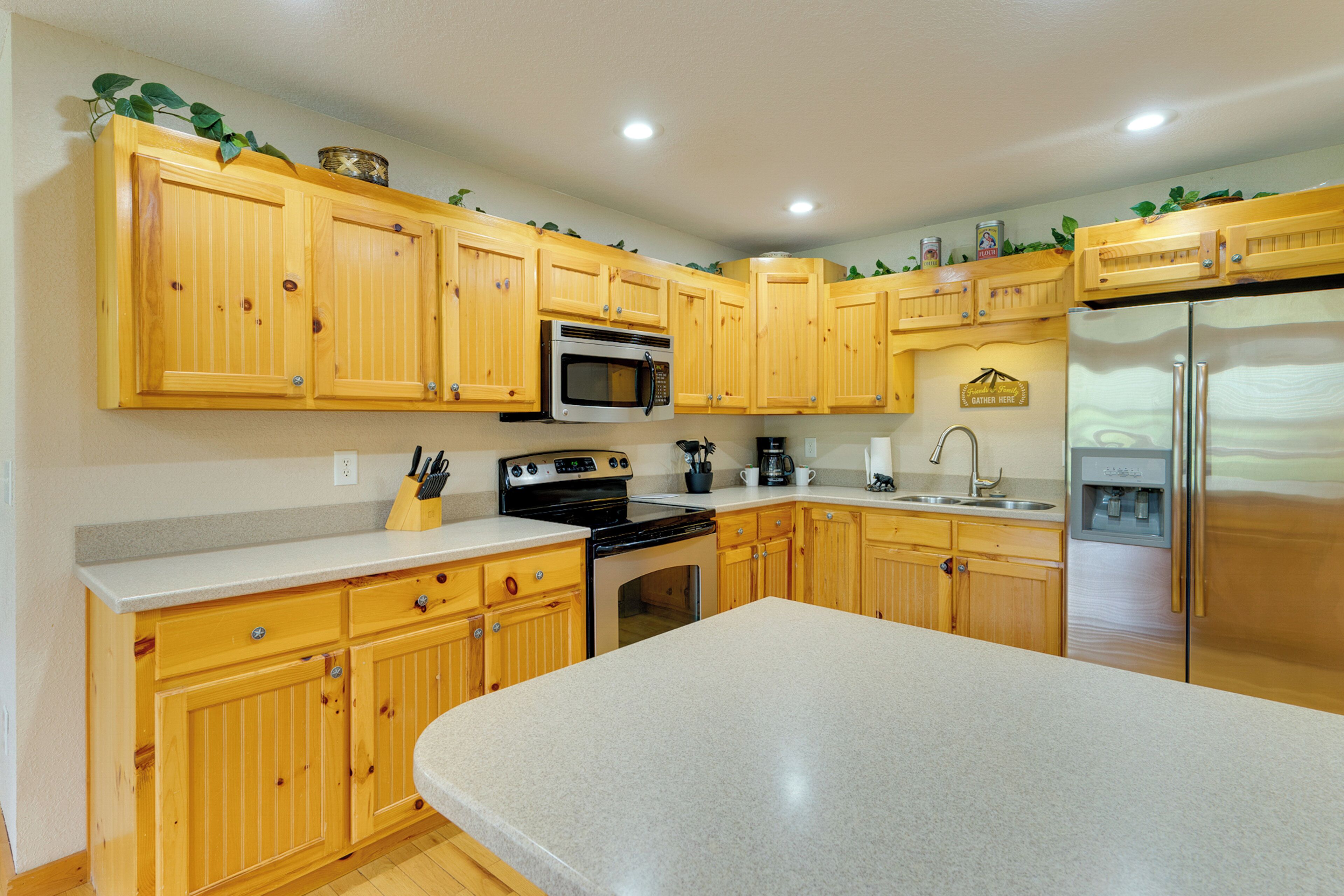 Una cocina con armarios de madera, un refrigerador de acero inoxidable, un microondas y una cafetera.
