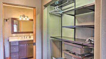 A bathroom with a vanity, mirror, and shelves with storage bins.
