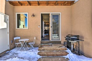 Un patio couvert avec un barbecue, une table pliante et des chaises.