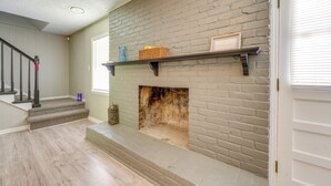 Une cheminée avec un mur en briques, un escalier en bois et une étagère au-dessus.