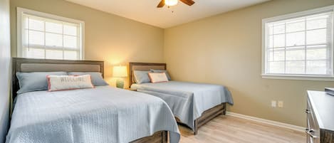 Un dormitorio con dos camas, un ventilador de techo y un aparador.
