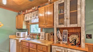 A kitchen with wooden cabinets, a microwave, a coffee maker, and a rustic decorative cabinet. - Cozy Pine Mountain Cabin w/ Screened Porch & Yard! (Pine Mountain)