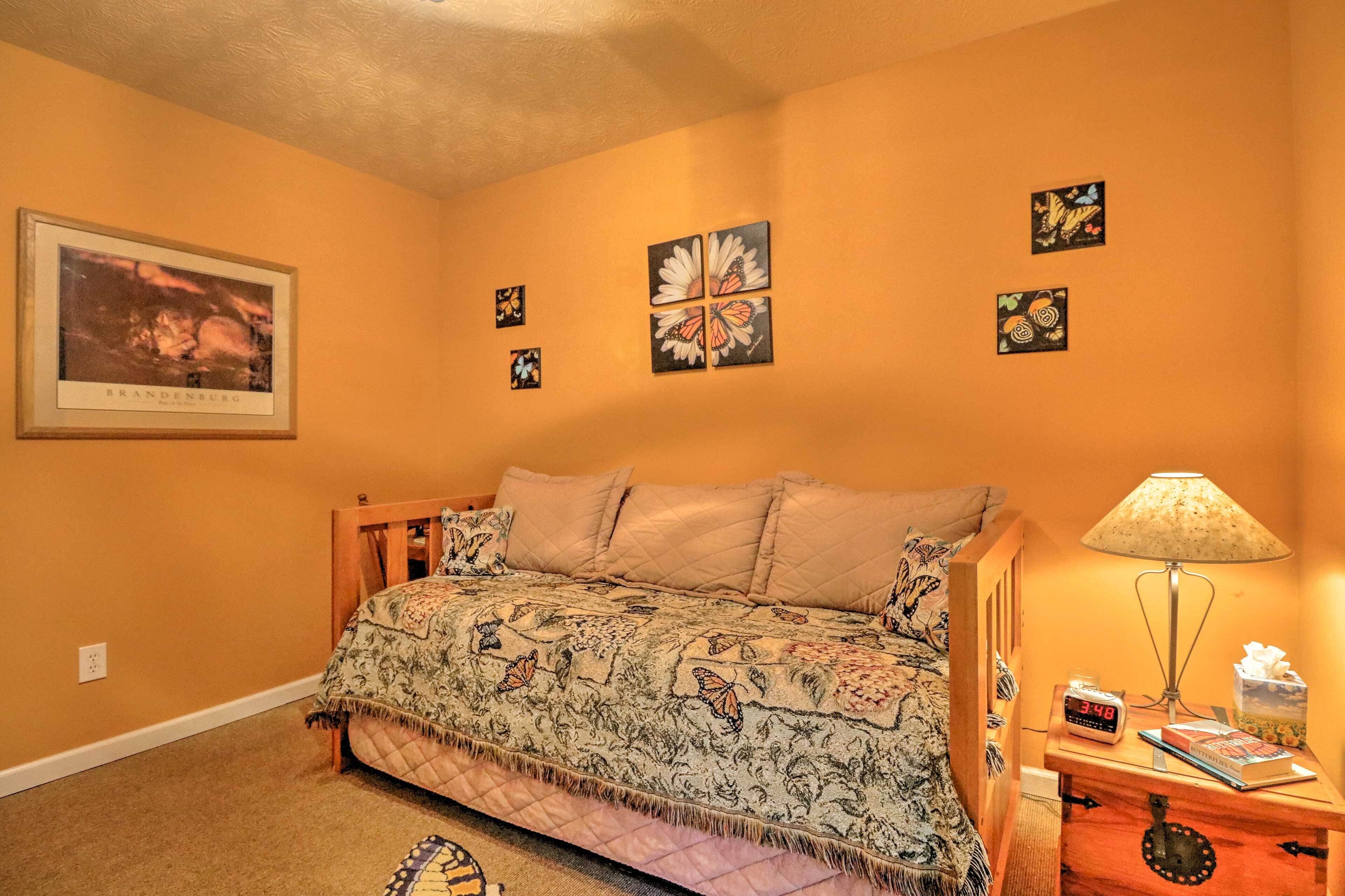 A bedroom with a bed, a nightstand, a lamp, a clock, and wall art.