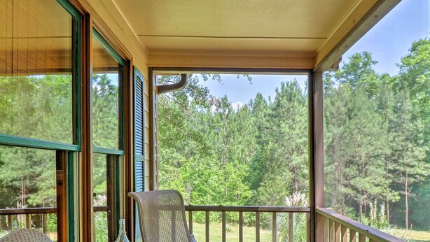 A covered porch with a table and two chairs, overlooking a wooded area. - Cozy Pine Mountain Cabin w/ Screened Porch & Yard! (Pine Mountain)
