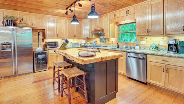 A spacious kitchen with wooden cabinets, stainless steel appliances, and a central island with stools. - Serene Riverfront Escape in Ellijay, Georgia! (Ellijay)