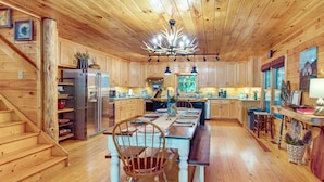 A wooden cabin interior with a dining area, kitchen, and staircase. - Serene Riverfront Escape in Ellijay, Georgia! (Ellijay)