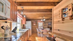 Interior de una cabaña de madera con cocina, comedor y estanterías empotradas.