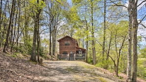 A rustic cabin with a porch, surrounded by tall trees and a dirt path leading to it. - Cozy Hiawassee Cabin w/ Fire Pit & Mtn Views! (Hiawassee)