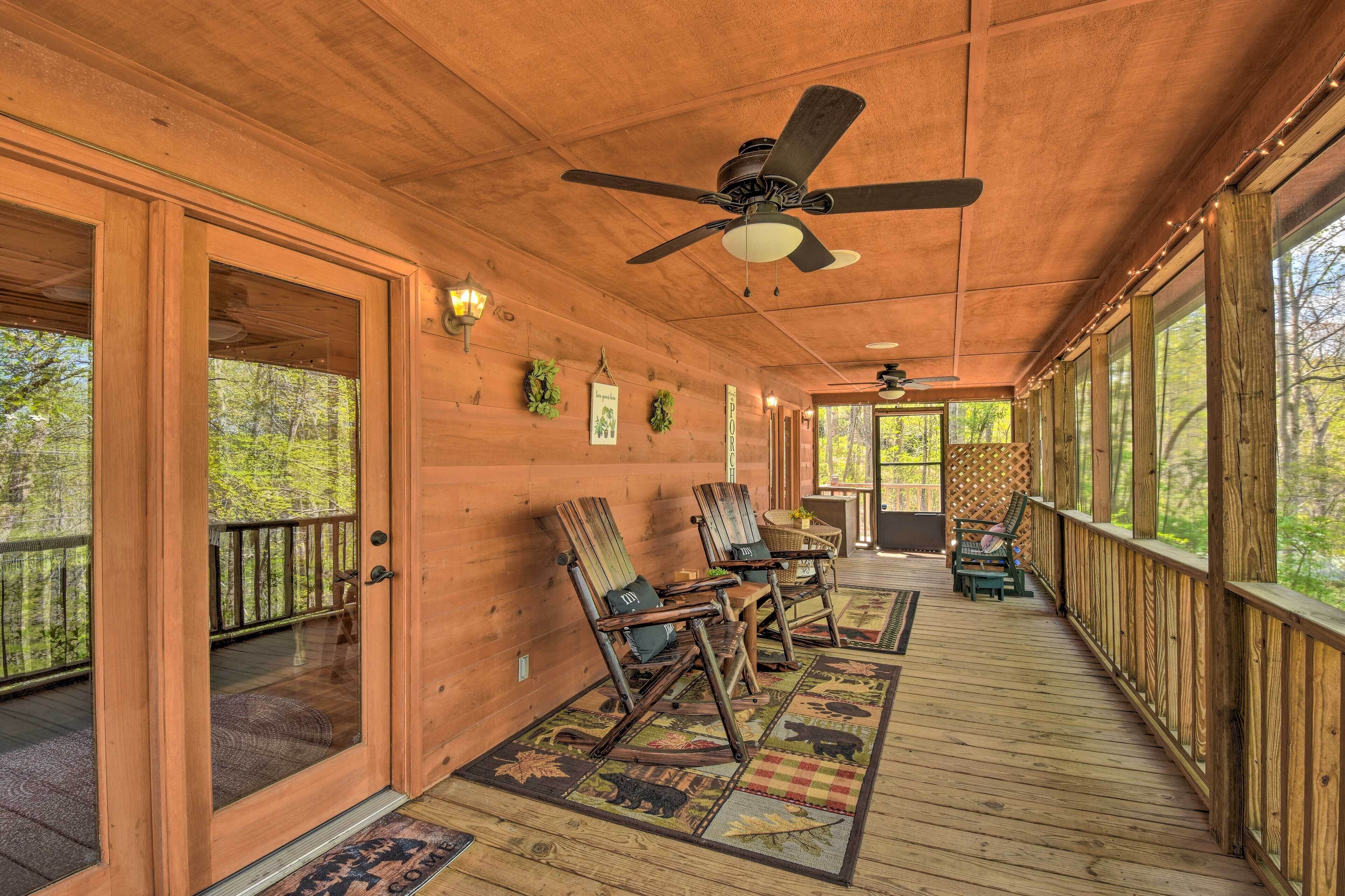 Une terrasse en bois avec des fauteuils à bascule, un ventilateur de plafond et une vue sur la forêt.