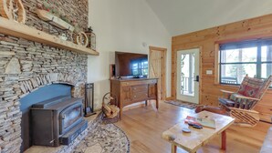 A cozy living room with a stone fireplace, wooden furniture, and a television. - Blairsville Cabin in the Pines 1 Mi to Lake (Blairsville)