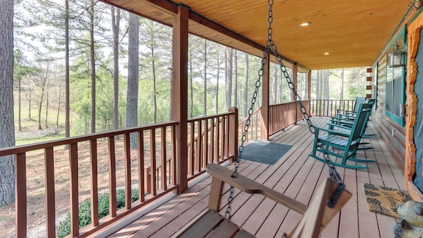 A wooden deck with a swing chair, a bench, and a view of a forest. - Blairsville Cabin in the Pines 1 Mi to Lake (Blairsville)