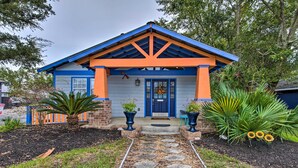 Ein Haus mit blau-orangem Anstrich, einer Veranda und einem steinernen Weg zum Eingang.