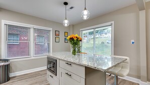 A kitchen with a marble countertop, a built-in oven, a bar stool, and a vase with flowers. - Modern Atlanta Vacation Rental Near Downtown! (Atlanta)