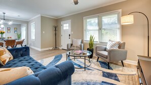 A living room with a blue sofa, a grey armchair, a coffee table, and a ceiling fan. - Modern Atlanta Vacation Rental Near Downtown! (Atlanta)