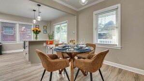 A dining area with a glass-top table, six brown chairs, and a vase of flowers. - Modern Atlanta Vacation Rental Near Downtown! (Atlanta)