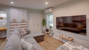 A modern living room with a grey sectional sofa, a large flat-screen TV, and a white wardrobe with multiple drawers. - Cozy Rising Fawn Studio ~ 4 Mi to Cloudland Canyon (Rising Fawn)