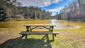 A picnic table by a calm lake surrounded by trees. - Game Room & Hot Tub: Upscale Ellijay Cabin! (Ellijay)