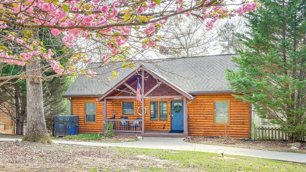 A wooden cabin with a porch, a flag, and a wreath on the door. - Game Room & Hot Tub: Upscale Ellijay Cabin! (Ellijay)