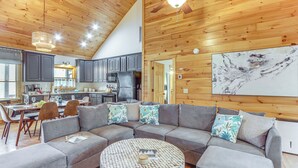 A spacious living area with a large gray sectional sofa, a round coffee table, and a ceiling fan. - Game Room & Hot Tub: Upscale Ellijay Cabin! (Ellijay)