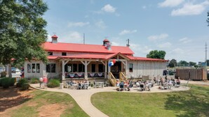 A building with a red roof and a covered outdoor seating area with tables and chairs. - Lake Oconee Abode w/ Patio, Grill & Fire Pit Table (Eatonton)
