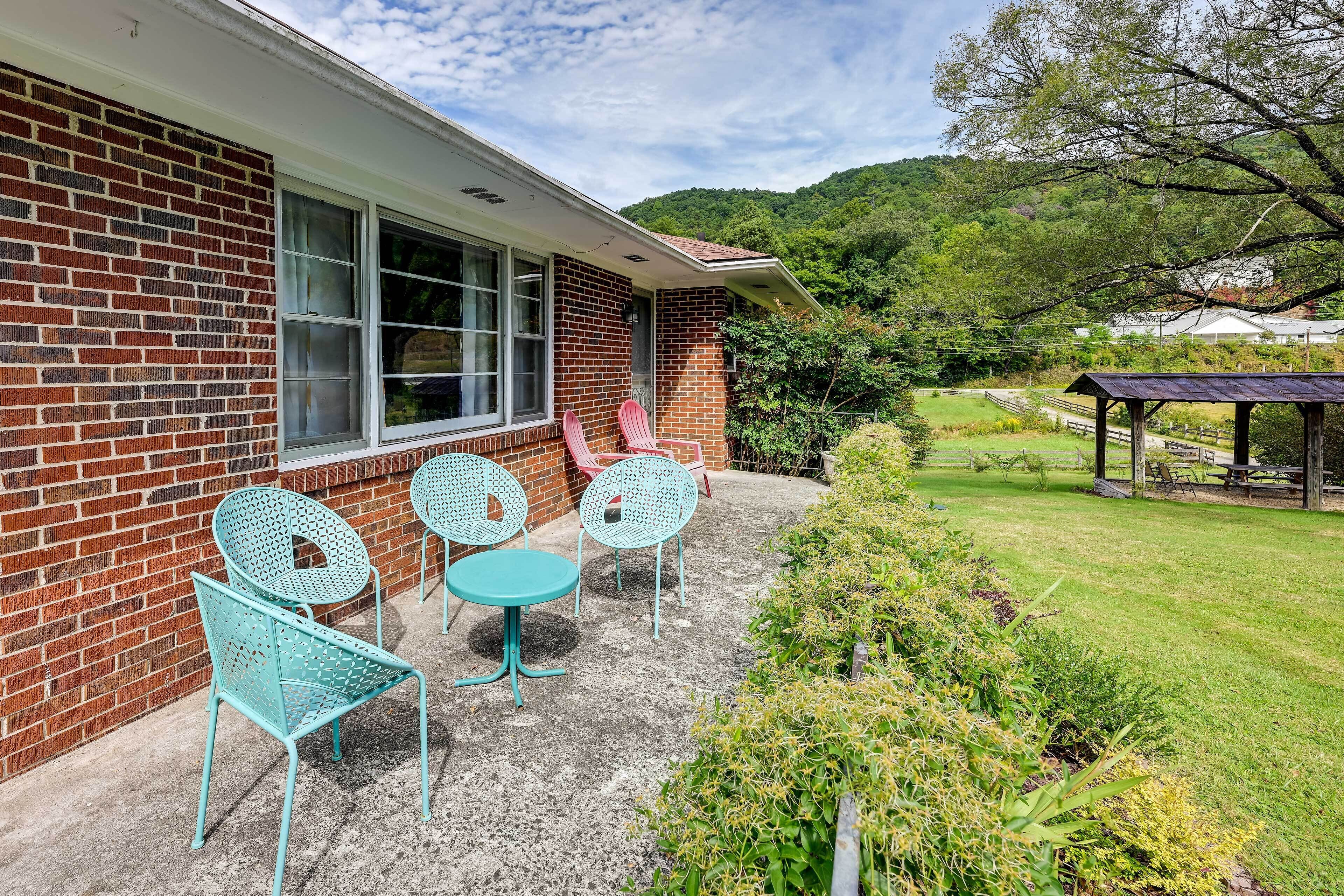 A brick building with a patio area featuring turquoise metal chairs and tables.