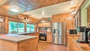 A kitchen with wooden cabinets, a stainless steel refrigerator, and a brick floor.