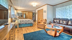 A cozy room with a bed, a leather sofa, a wooden coffee table, and a blue rug.
