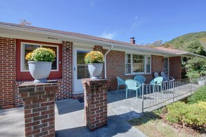 A two-story brick house with a red door, large flower pots, and a patio with blue chairs. - Pet Friendly Home w/ Hot Tub, Patio & Game Room! (Clayton)
