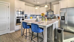 A modern kitchen with white cabinetry, stainless steel appliances, and blue bar stools. - Waterfront Paradise w/ Deck ~ 1/2 Mi to Beach (Norfolk)
