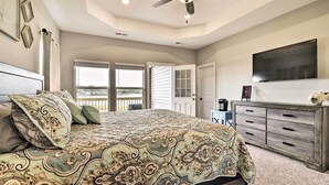 A bedroom with a large bed, a ceiling fan, a TV, and a sliding glass door leading to a balcony. - Waterfront Paradise w/ Deck ~ 1/2 Mi to Beach (Norfolk)