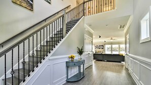 A spacious hallway with a staircase, a console table with a vase, and a seating area with a view of the outdoors. - Waterfront Paradise w/ Deck ~ 1/2 Mi to Beach (Norfolk)