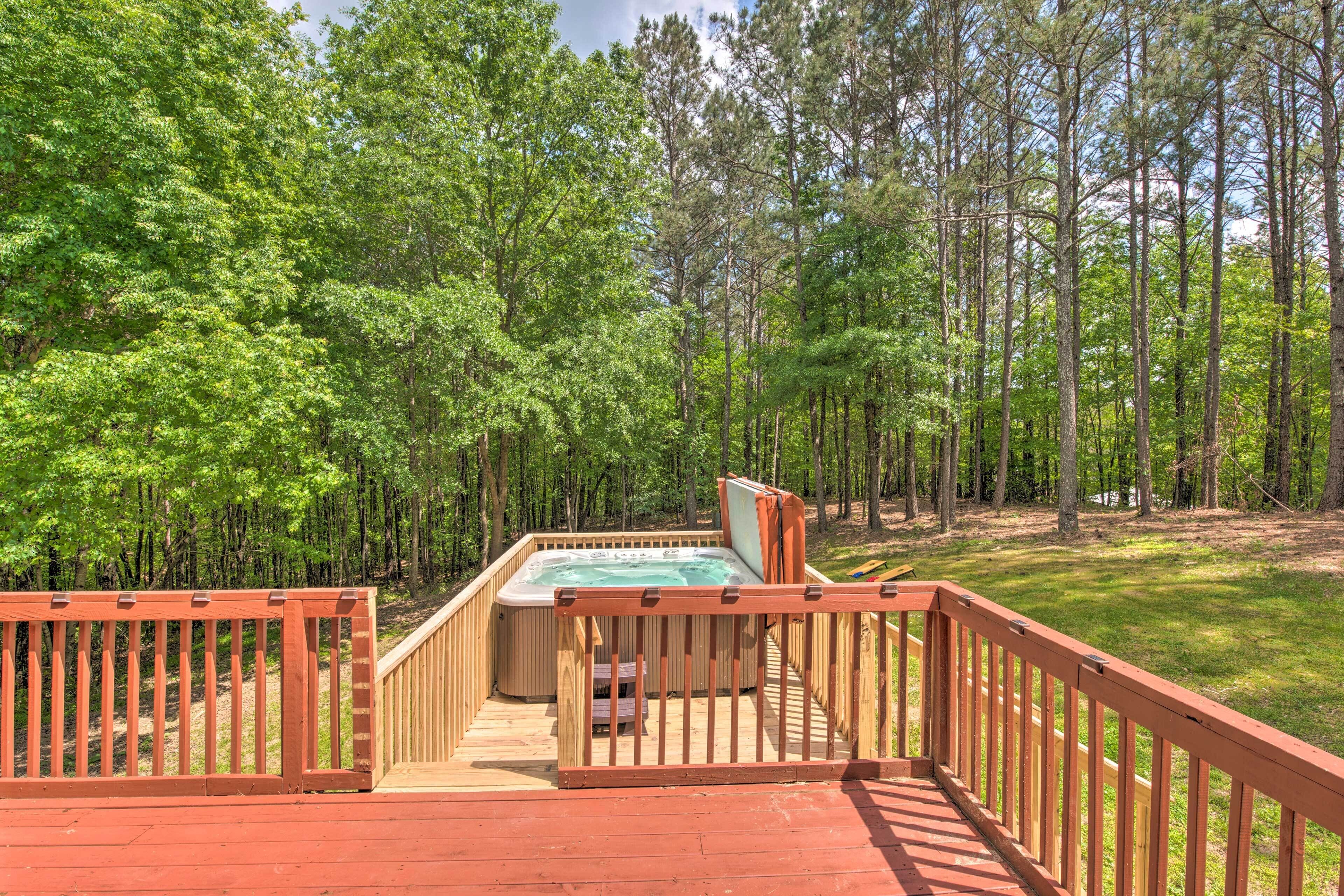 Un jacuzzi en una terraza de madera rodeado por un bosque.