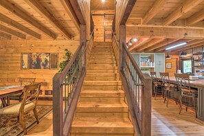 Una escalera de madera que conduce a una zona de bar con sillas de madera y una barra.