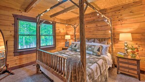A wooden cabin bedroom with a four-poster bed, two bedside tables, and a window with a view of greenery. - Rural Dallas Gem w/ Hot Tub, Sauna + Fire Pit! (Dallas)