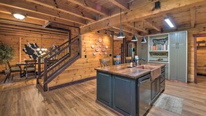 A wooden interior with a kitchen island, dining area, and a staircase. - Rural Dallas Gem w/ Hot Tub, Sauna + Fire Pit! (Dallas)