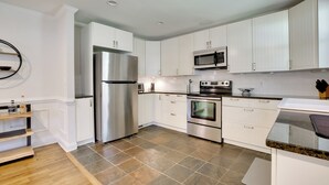 A modern kitchen with white cabinets, stainless steel appliances, and a wooden floor. - Contemporary Athens Home < 2 Miles to Uga! (Athens)