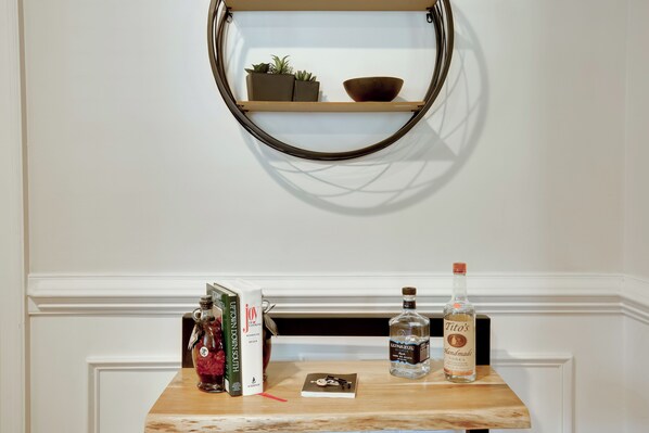 A shelf with books, a bottle of vodka, and a decorative item. - Contemporary Athens Home < 2 Miles to Uga! (Athens)
